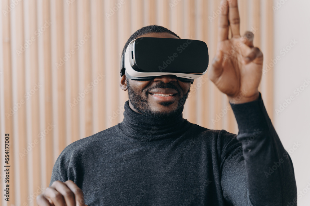 Excited African American man in VR headset glasses enjoying augmented reality in office Excited African American man in VR headset glasses enjoying augmented reality in office