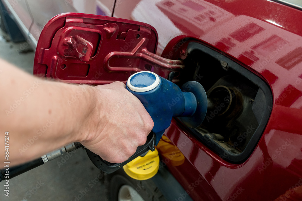 A man hand holding pump filling gasoline. Pumping petrol into the tank. A car refuel on gas station A man hand holding pump filling gasoline. Pumping petrol into the tank. A car refuel on gas station