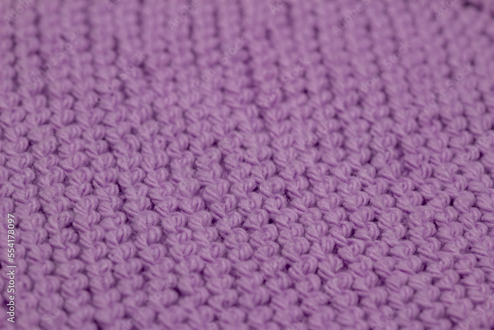 Macro defocused abstract texture background of a hand-knitted lavender color cloth in a garter stitch pattern