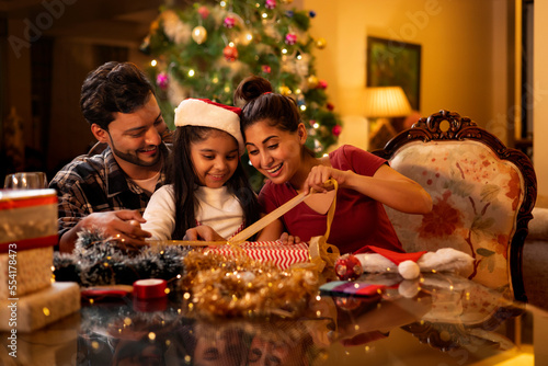 Happy family wrapping Christmas presents together at home