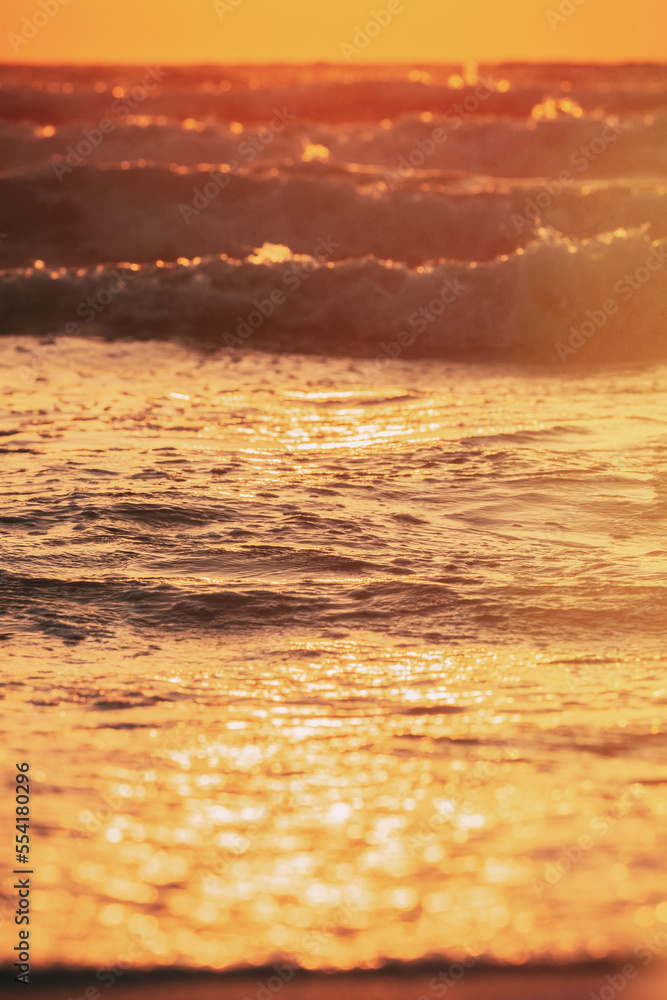 Sunset above sea. Natural sunrise sky warm colors over ripple sea with small waves. Ocean water foam splashing. Beautiful seascape in sunset sunrise time. Vertical photo. Sunset above sea. Natural sunrise sky warm colors over ripple sea with small waves. Ocean water foam splashing. Beautiful seascape in sunset sunrise time. Vertical photo.