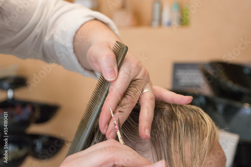 Une coiffeuse coupe les cheveux d'une cliente dans un salon de coiffure
