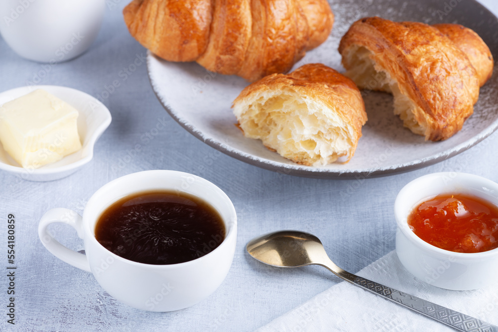 A freshly baked French Croissant, coffee, butter and jam