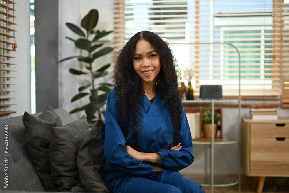 Healthcare worker or caregiver in uniform sitting with crossed arms and looking at camera. Home health care service concept Healthcare worker or caregiver in uniform sitting with crossed arms and looking at camera. Home health care service concept