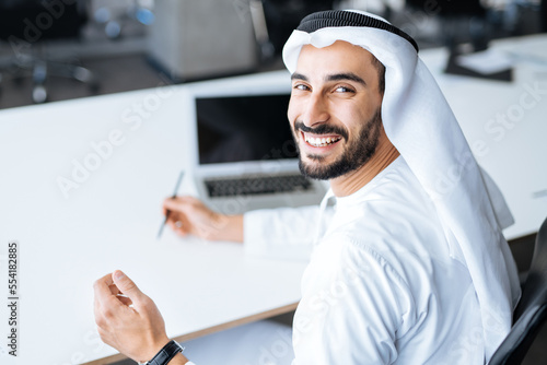 Photography handsome man with dish dasha working in his business office of Dubai