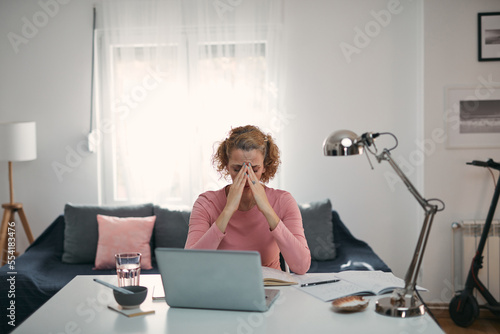 Woman with eyes hurting, sinus problem, headache, head pain, working from home troubles and issues. photo