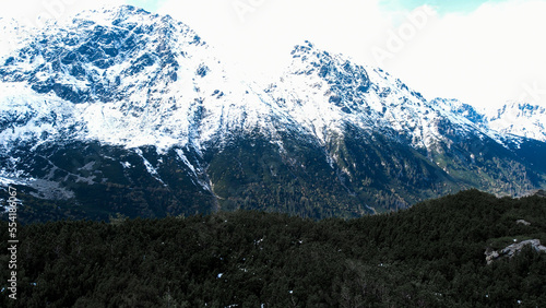 lake near the Morskie Oko Snowy Mountain Hut in Polish Tatry mountains, drone view, Zakopane, Poland. Aerial view shot of beautiful green hills and mountains in dark clouds and reflection on the lake