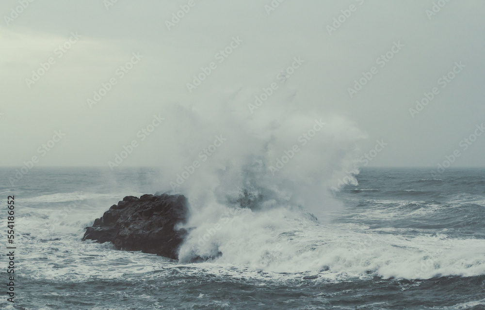 Splash sea water over rock on storm landscape photo. Beautiful nature scenery photography with mist on background. Idyllic scene. High quality picture for wallpaper, travel blog, magazine, article