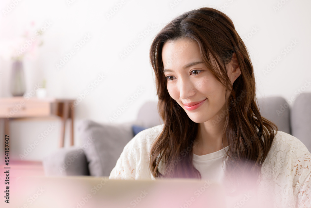 メインビジュアルにも!パソコンをで仕事をする女性 春っぽいピンクの前ボケあり アップ メインビジュアルにも!パソコンをで仕事をする女性 春っぽいピンクの前ボケあり アップ