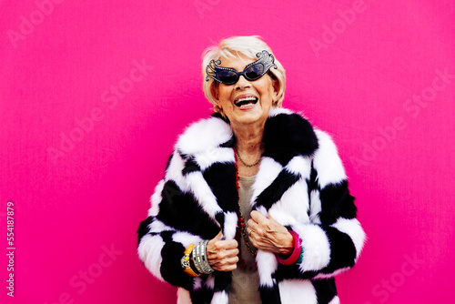 Happy and funny  grandmother posing on colored backgrounds. Old woman having fun and celebrating. Concept about third age and seniority