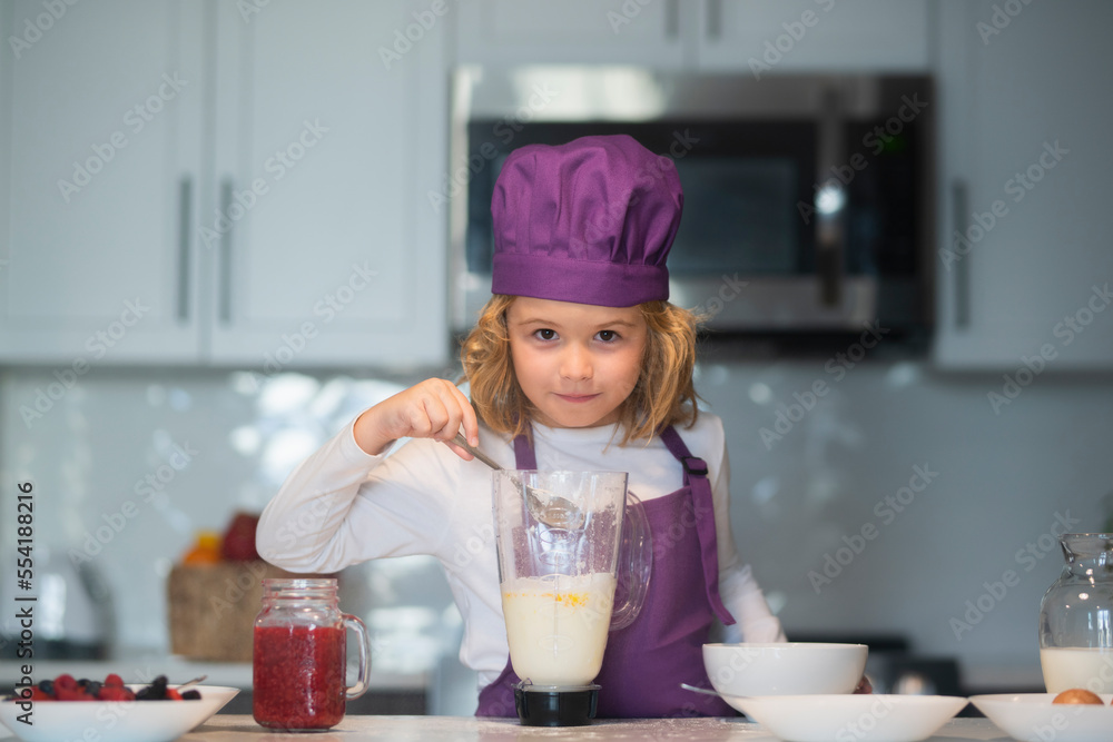 Kid in chef hat and apron. Kids are preparing the dough, bake cookies in the kitchen. Kid in chef hat and apron. Kids are preparing the dough, bake cookies in the kitchen.