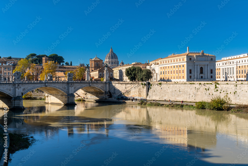 view of downtown Rome on the banks of the Tiber River with Saint Peter's Basilica in the background