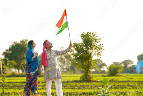 Indian farmer couple waving tricolor national flag at agriculture field. photo