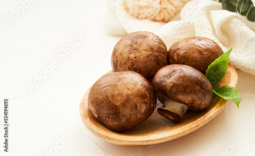 brown champignon button mushroom and green leaf in wood bowl on white table background. pile of brown champignon button mushroom. 