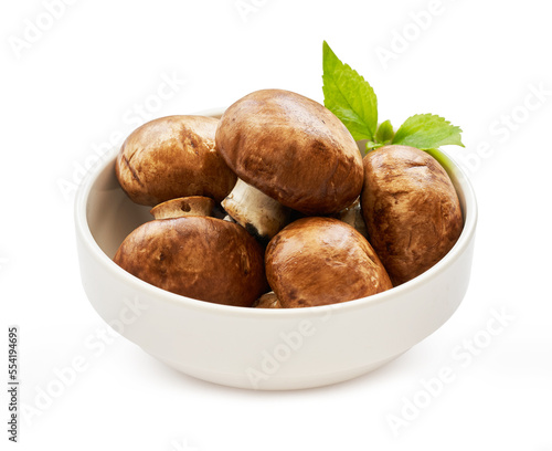 brown champignon button mushroom and green leaf in white bowl isolated on white background. pile of brown champignon button mushroom. 