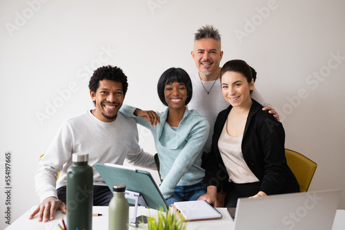 Portrait with group of five mixed race teamwork in office. People smiling looking at camera.