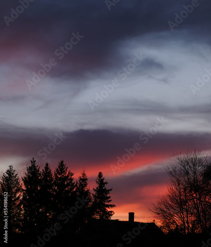 Colorful sky at sunset - in the background the contour of the house and trees