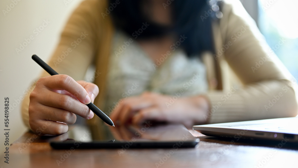 An Asian woman using her tablet, remote working at the coffee shop. cropped image An Asian woman using her tablet, remote working at the coffee shop. cropped image