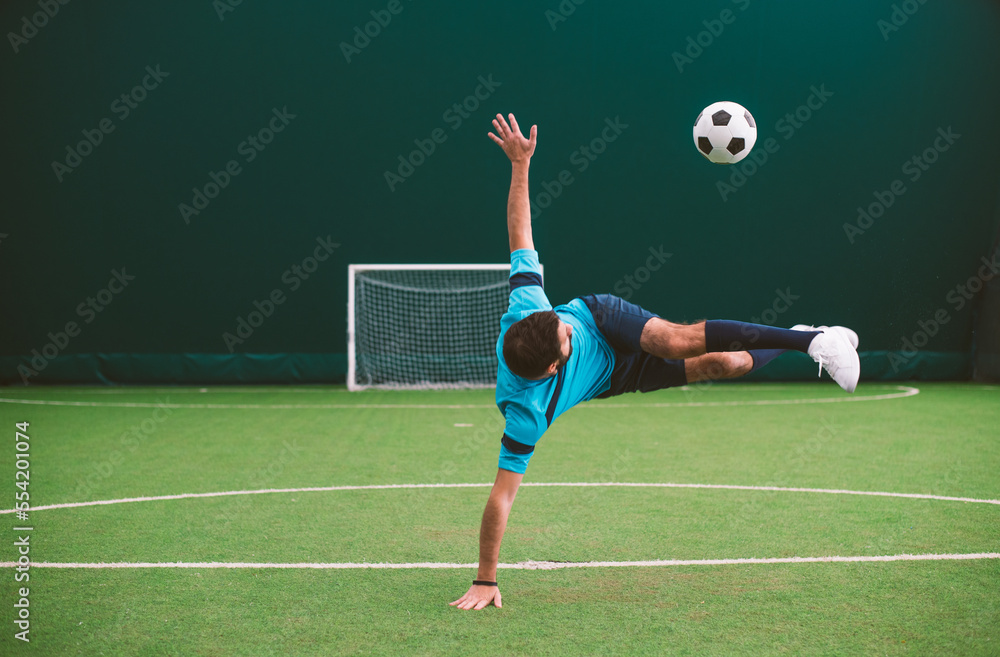 Cinematic image of a soccer freestyle player making tricks with the ball on a artificial grass court indoor. Concept about sport and people lifestyle Cinematic image of a soccer freestyle player making tricks with the ball on a artificial grass court indoor. Concept about sport and people lifestyle