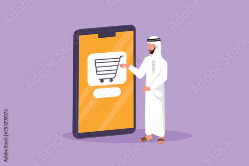 Cartoon flat style drawing Arab man standing and buying online via giant smartphone screen with shopping cart inside. Sale, digital lifestyle, consumerism concept. Graphic design vector illustration