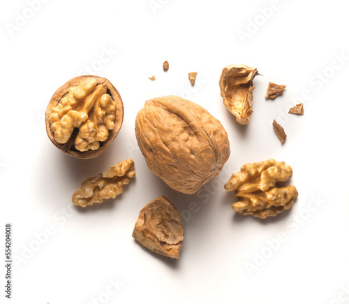 whole walnut plus open walnut with scattered shell parts on white background
