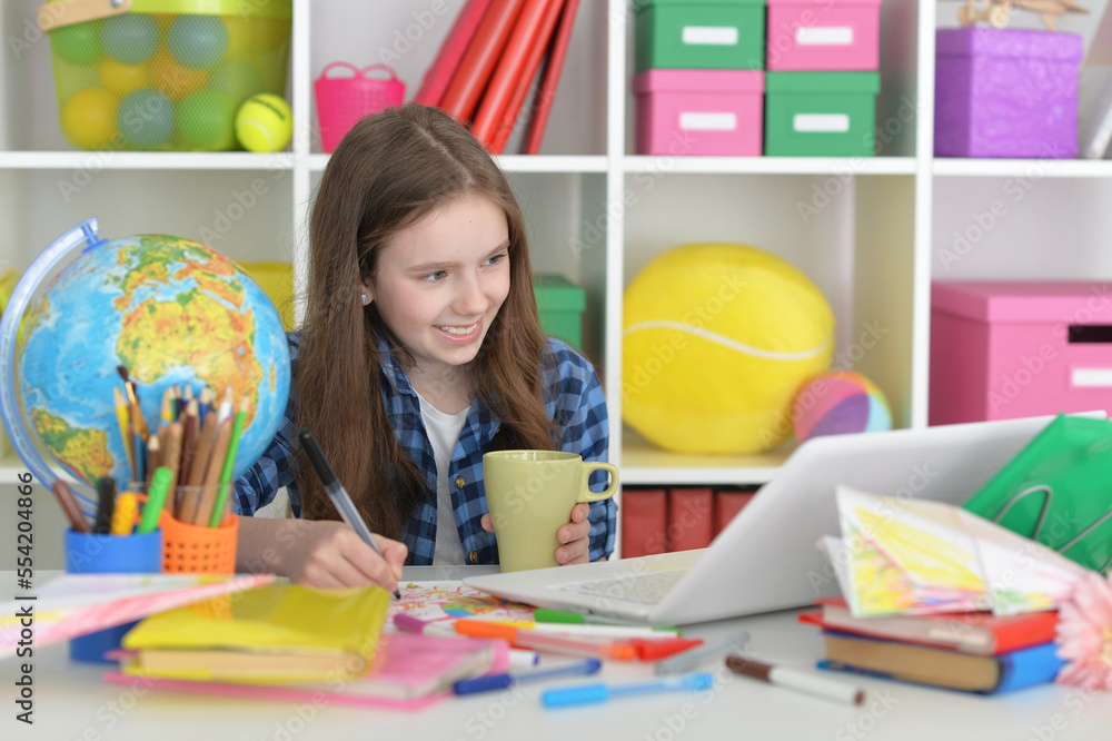 girl with cup using laptop at home at desk girl with cup using laptop at home at desk