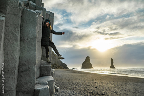 posing woman is indulging on basaltic rock at Reynisfjara black Beach