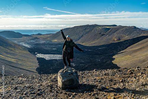 young woman poses for camera on the rock at Fagradalsfjall volcano valley in iceland