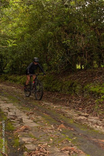 Sporty woman riding her bike while descending the mountain on a stone path