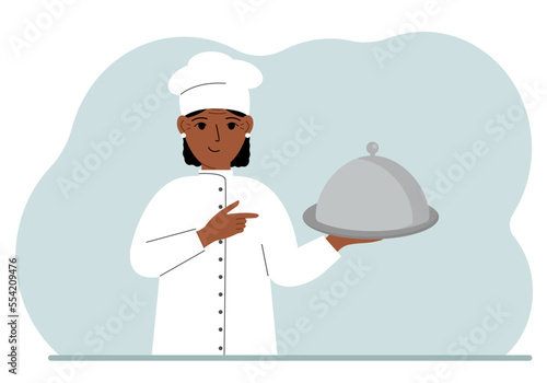 A female chef with a plate covered with a cloche or a tray with a lid.
