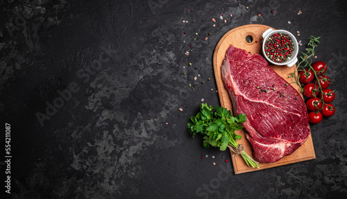 Fresh and raw beef meat. Whole piece of tenderloin with steaks and spices ready to cook on dark background, banner, menu, recipe place for text, top view