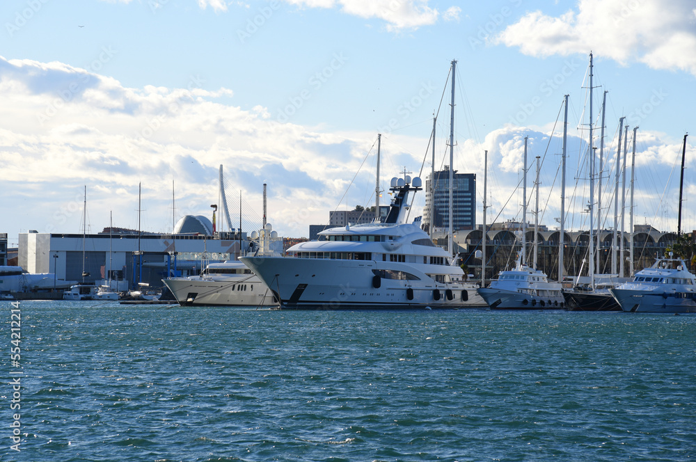 Naklejka premium Yacht in La Marina de Valencia, Spain. Luxury yachts and motorboat in yacht club at Mediterranean Sea. Skiff and Sailboat in port. Yachting and sailing sport. Marina parking of boats and yachts.
