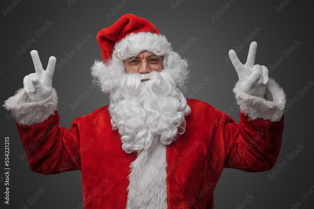 Portrait of isolated on grey santa claus with glasses dressed in red suit and hat.