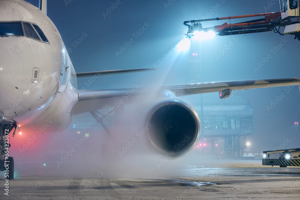 Deicing of airplane before flight. Winter night at airport during snowfall.. Deicing of airplane before flight. Winter night at airport during snowfall..