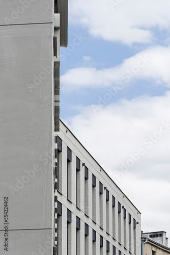 Detal na obiekt biurowy. Elewacja wykonana z betonu. Harmonijny i spójny układ okien. Spadek terenu.