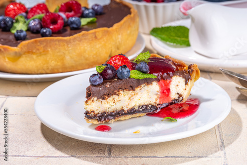 Homemade cheesecake with chocolate and berry. Sweet cottage cheese cake pie with fresh and chocolate topping  classic dessert om beige tiled table copy space