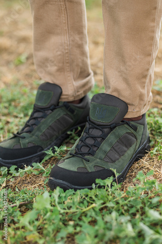 A military man in a special uniform and protective tactical sneakers. Special waterproof sneakers for soldiers in khaki and green