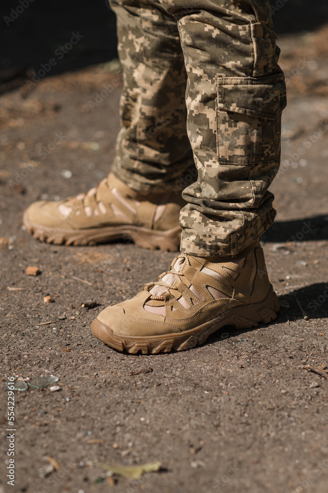 A military man in a special uniform and protective tactical sneakers. Special waterproof sneakers for soldiers in khaki and green A military man in a special uniform and protective tactical sneakers. Special waterproof sneakers for soldiers in khaki and green