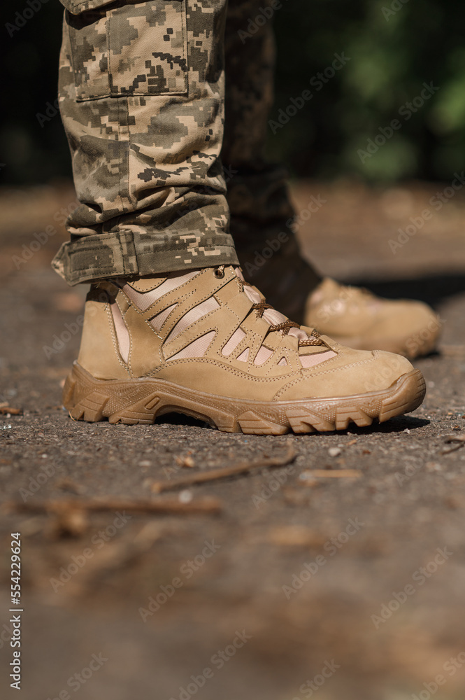 A military man in a special uniform and protective tactical sneakers. Special waterproof sneakers for soldiers in khaki and green