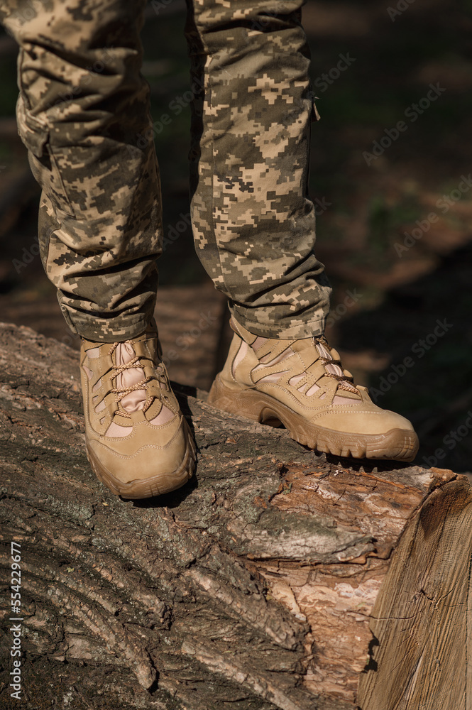 A military man in a special uniform and protective tactical sneakers. Special waterproof sneakers for soldiers in khaki and green