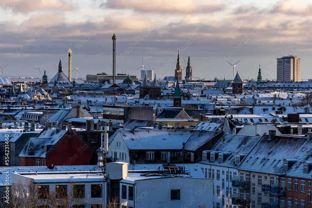 Copenhagen, Denmark Snow covers the rooftops of the city skyline, church spires, and wind turbines.