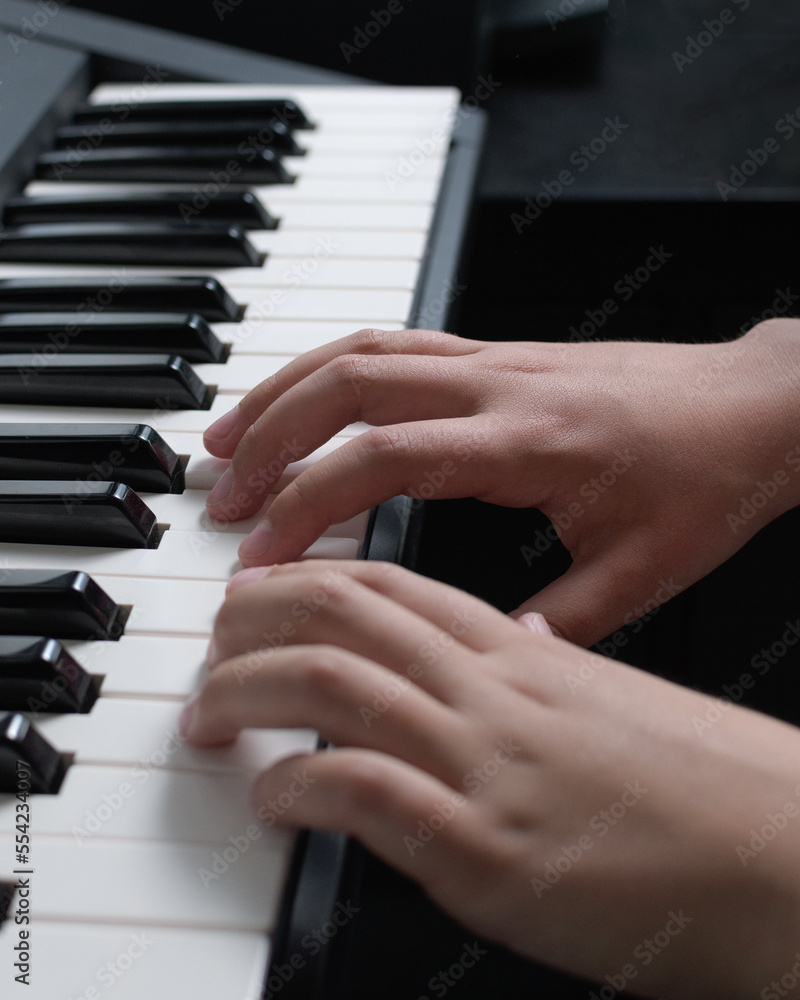 Music playing practice. Two hands on the piano keyboard. Notes chords and scales close-up