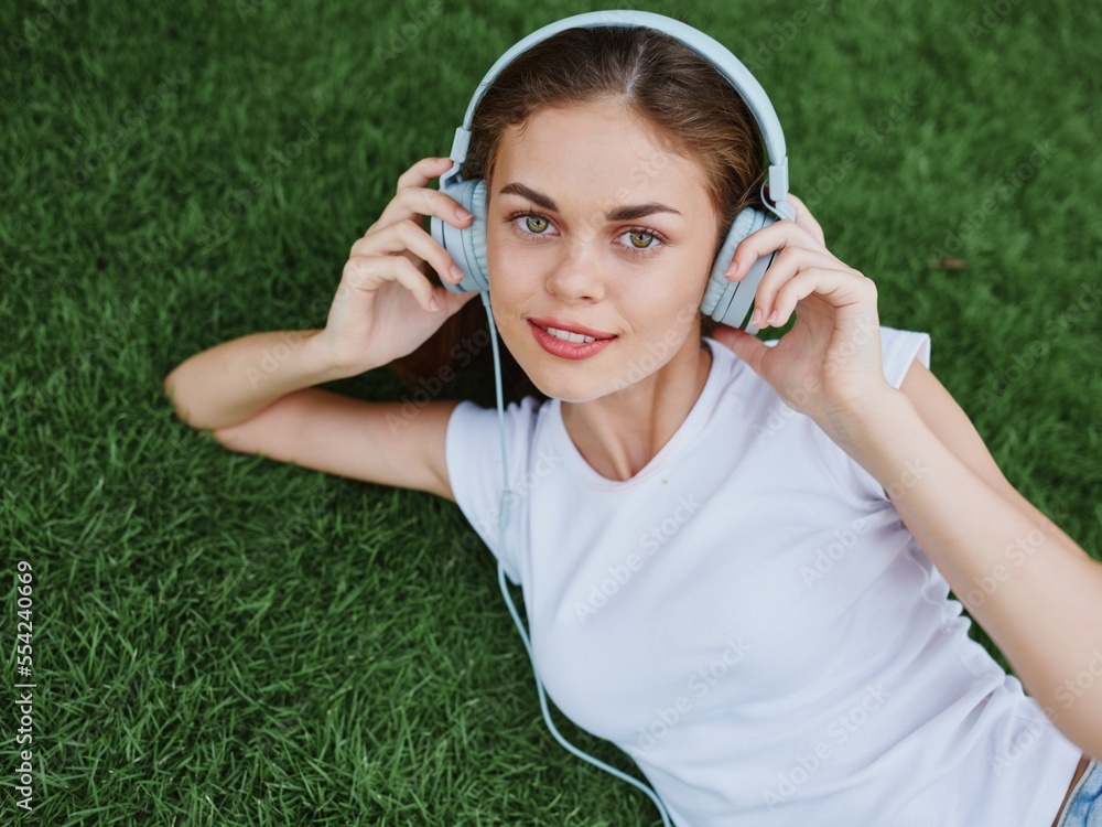Woman happiness smile in the park lying on the green grass in the summer with headphones Woman happiness smile in the park lying on the green grass in the summer with headphones