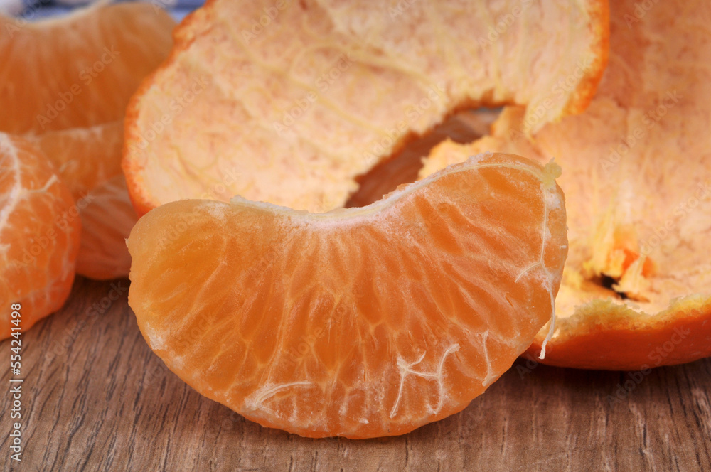 Quartier de mandarine en gros plan avec son écorce au second plan Quartier de mandarine en gros plan avec son écorce au second plan
