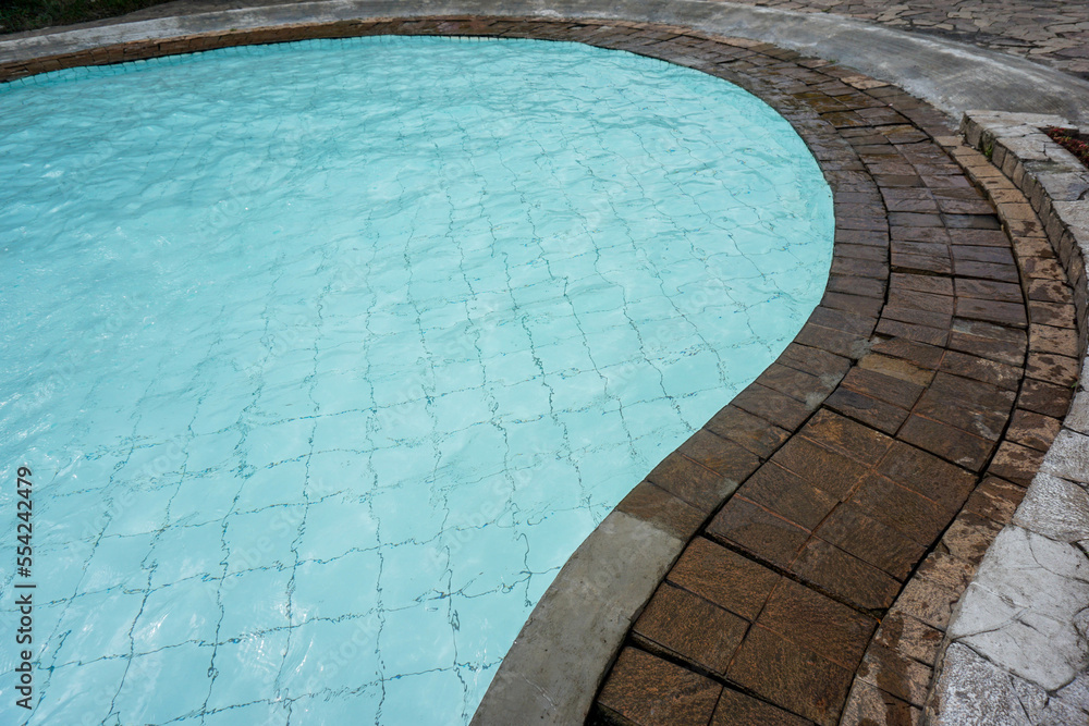 curving swimming pool bord, water and natural stone texture. copy space