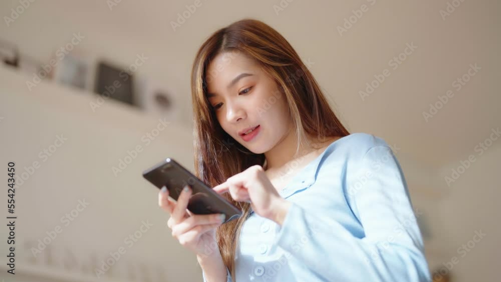 Happy young asian woman relax on comfortable couch at home texting messaging on smartphone, smiling girl use cellphone chatting, browse wireless internet on gadget, shopping online from home Happy young asian woman relax on comfortable couch at home texting messaging on smartphone, smiling girl use cellphone chatting, browse wireless internet on gadget, shopping online from home