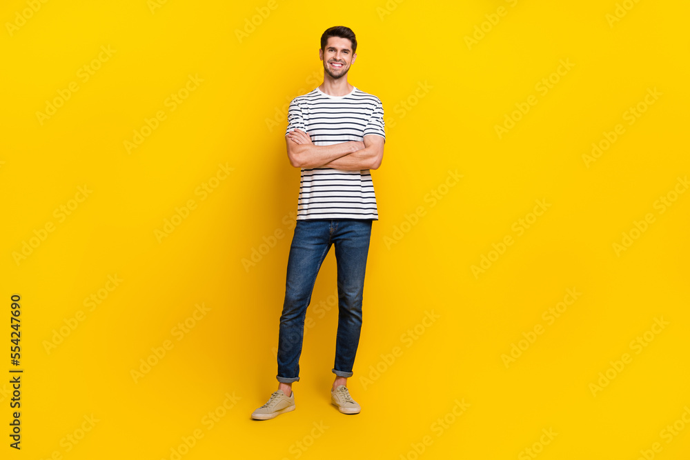 Full length photo of cheerful charming guy dressed striped t-shirt arms crossed isolated yellow color background Full length photo of cheerful charming guy dressed striped t-shirt arms crossed isolated yellow color background