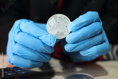 silver australian coin in hands with gloves over the table