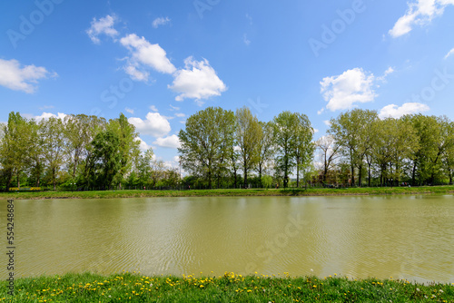 Small lake with a woodmill and an island from Chindiei Park (Parcul Chindiei) in Targoviste, Romania, in a sunny spring day with white clouds and blue sky photo
