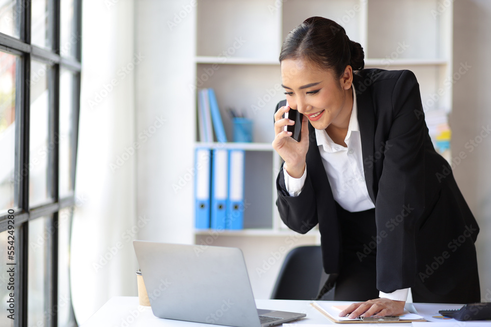 Attractive businesswoman in office is using mobile phone to talk with colleagues and business partners. Attractive businesswoman in office is using mobile phone to talk with colleagues and business partners.